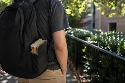 Campus Student Carrying Bible in Backpack