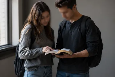 College Students Reading Bible in Campus Hallway