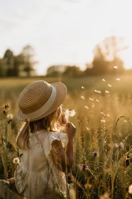 Child Blowing Dandelion Seeds in Summer Meadow