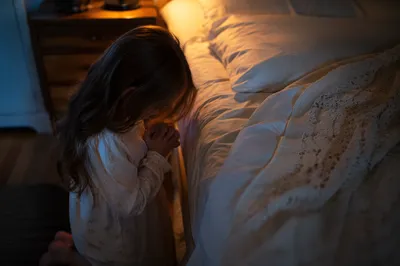 Child Praying Beside Bed at Night