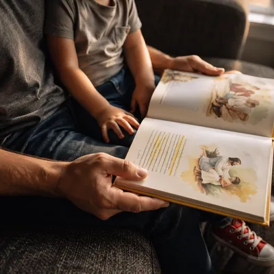 Child Reading Picture Bible on Parent’s Lap