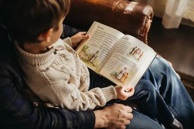 Child Reading Picture Bible on Parent Lap