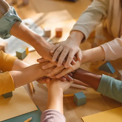 Children Stacking Hands in Classroom Teamwork