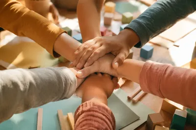 Children’s Hands Stacked in Classroom Teamwork