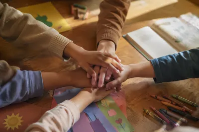 Children’s Hands Stacked in Classroom Teamwork