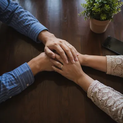 Couple Praying Together at Wooden Table