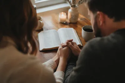 Couple Praying Together at Kitchen Table