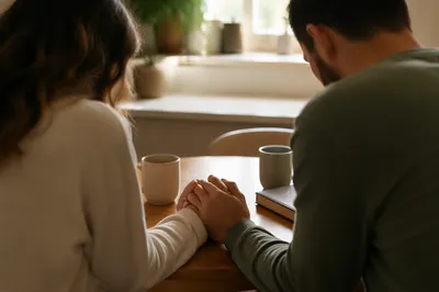 Couple Praying Hand in Hand at Kitchen Table