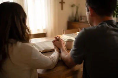 Couple Praying Together at Sunrise Table