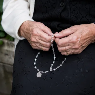 Elderly Hands Holding Rosary in Prayer