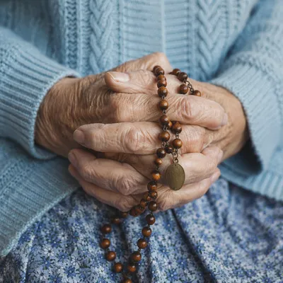Elderly Hands Praying With Wooden Rosary