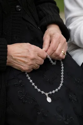 Elderly Hands Holding Rosary in Prayer