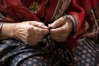 Elderly Hands Holding Rosary Beads in Prayer