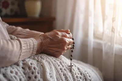 Elderly Hands Holding Rosary in Prayer