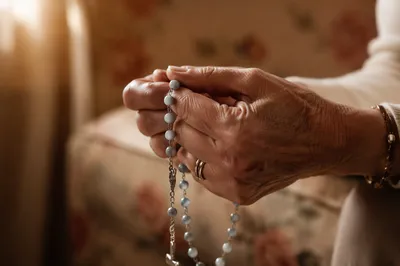 Elderly Hands Holding Rosary in Prayer