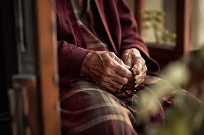 Elderly Hands Holding Rosary in Prayer