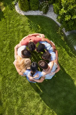 Friends Embracing in Circle on Green Lawn