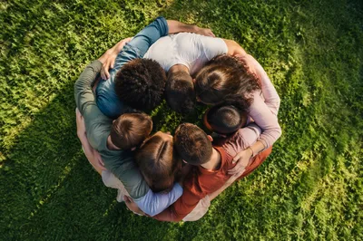 Overhead Friends Group Hug on Sunlit Lawn