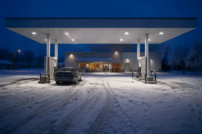 Evening Car Fueling at Snowy Gas Station