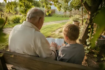 Grandfather and Grandchild Reading Bible in Garden