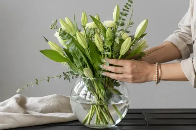Hands Arranging Ivory Flowers in Glass Vase