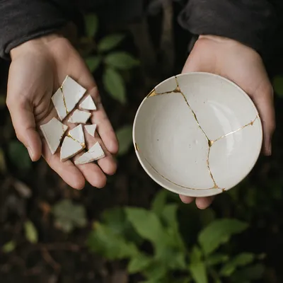 Hands Holding Kintsugi Pottery in Garden