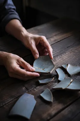 Hands Restoring Broken Pottery With Gold