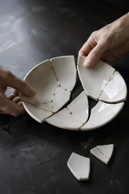Hands Restoring Broken Pottery With Gold Kintsugi