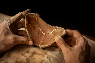Hands Holding Kintsugi Pottery in Warm Light