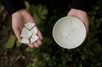 Hands Holding Kintsugi Pottery in Garden