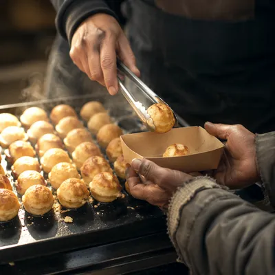 Volunteer Hands Serving Warm Pastries to Homeless