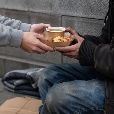 Volunteer Hands Sharing Meal with Homeless Neighbor