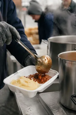 Volunteer Hands Serving Stew to Homeless Neighbors