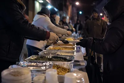 Hands Serving Warm Meals on City Sidewalk