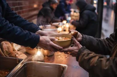 Compassionate Hands Serving Soup Outdoors