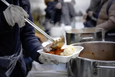 Volunteer Hands Serving Stew to Unhoused Neighbors