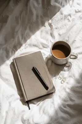 Coffee Mug and Journal on White Bedding