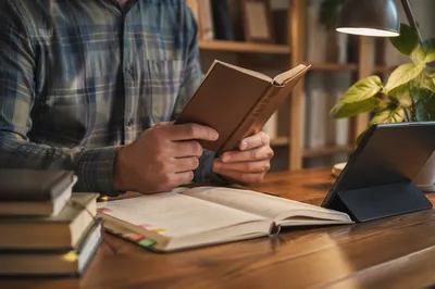 Man Reading Bible by Desk Lamp