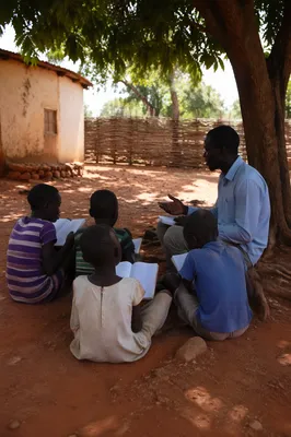 Missionary Teaching Children Under African Shade Tree