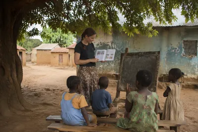 Missionary Teaching Children Under African Shade Tree