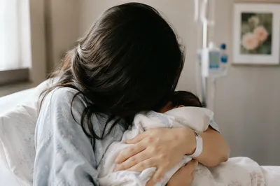 New Mother Cradling Newborn in Gentle Hospital Light