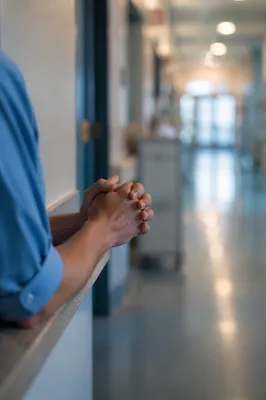 Nurse Praying in Quiet Hospital Corridor