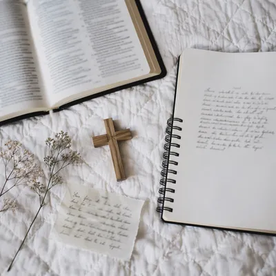 Open Notebook and Book on White Quilt
