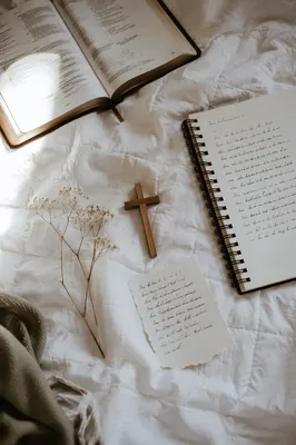 Open Notebook and Book on White Quilt