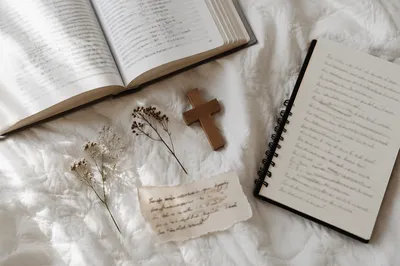 Open Notebook and Book on White Quilt