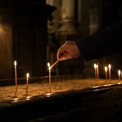 Hand Lighting Votive Candle in Dark Chapel