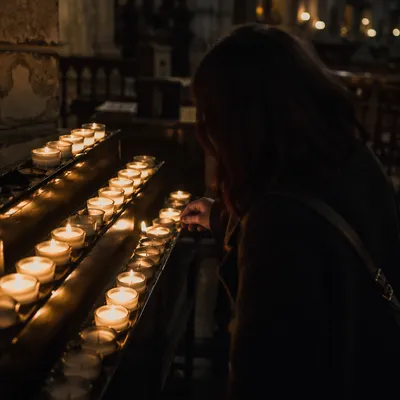 Person Lighting Votive Candle in Dark Church