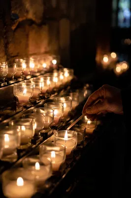 Hand Lighting Votive Candle in Dark Church