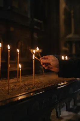 Hand Lighting Votive Candle in Dark Chapel