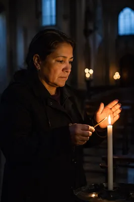 Woman Lighting Candle in Dim Church